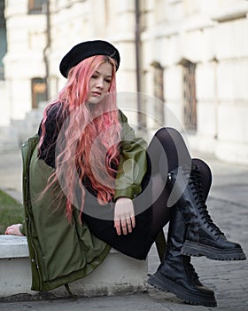 Student in a black beret with long pink hair sits on the steps resting dreaming of a vacation