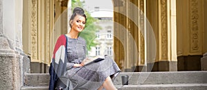 Student with book sitting on stairs