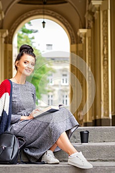 Student with book sitting on stairs