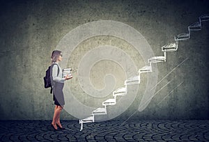 Student with books standing on the stairs of education leading to success