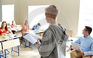 Student boy with notebook and teacher at school