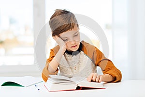 Student boy reading book or textbook at home