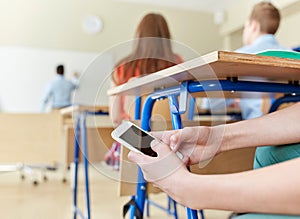 Student boy with smartphone texting at school photo