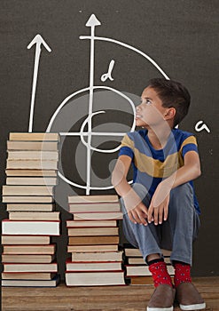 Student boy on a table looking up against grey blackboard with school and education graphic