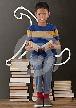 Student boy on a table reading against grey blackboard with school and education graphic