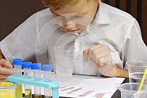 Student boy tinkering with test tubes. The child does experiments at home. Children`s home lab