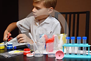 Student boy tinkering with test tubes. The child does experiments at home. Children`s home lab