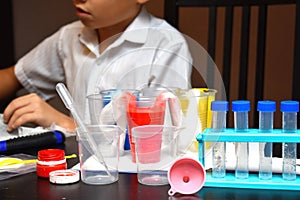 Student boy tinkering with test tubes. The child does experiments at home. Children`s home lab