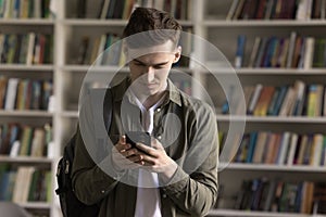 Student checks mobile phone message standing in university library