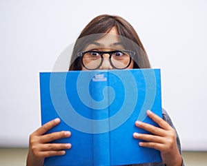 Student, child and hide face with book to read in front for classroom, shy and learning. Elementary school, girl kid and