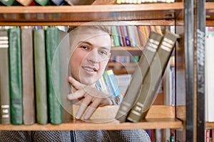 Student chooses a book on a shelf in the library