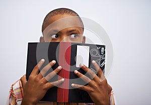 Student, classroom and hide face with book to read in front for classmates, shy and learning. Elementary school, boy and