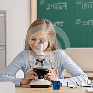 Student in classroom peering into microscope photo