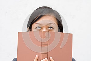 Student covering her face with book