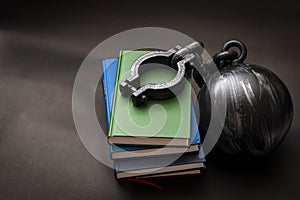 Student debt concept with a stack of books next to a ball and chain symbolizing the burden tuition costs represent with copy space