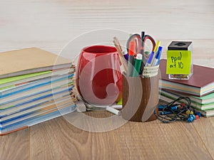 Student desktop and stack  books,  accessories, stationery, red mug, crayons