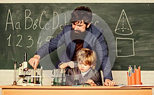 student doing science experiments with microscope in lab. father and son at school. using microscope in lab. Back to