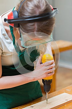 Student drilling a hole in a wooden board at the workbench