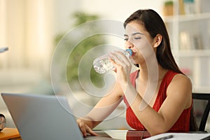 Student drinks water from bottle at home