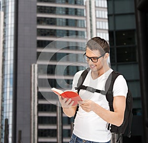 Student in eyeglasses with backpack and book