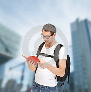 Student in eyeglasses with backpack and book