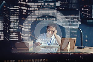 Student falling asleep while studying at a desk. Office room shot behind the glass.