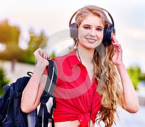 Student girl with backpack in headphone listen music after exam.