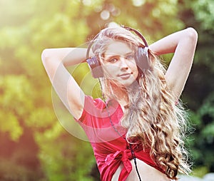 Student girl with backpack headphone listen music on green grass