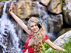 Student girl with backpack headphone listen music on green grass
