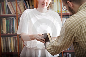 Student girl borrows a book from a boy in a classroom