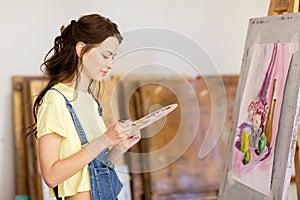 Student girl with easel painting at art school
