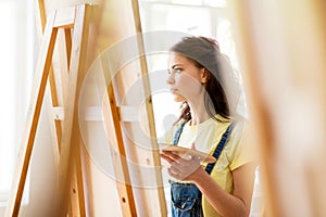 Student girl with easel painting at art school