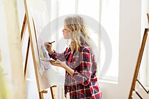 Student girl with easel painting at art school