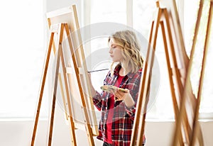 Student girl with easel painting at art school