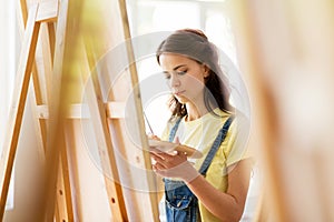 Student girl with easel painting at art school