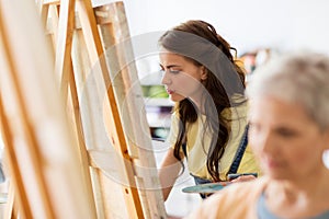 Student girl with easel painting at art school