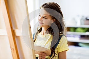 Student girl with easel painting at art school