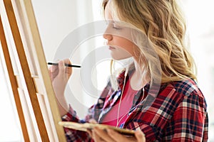 Student girl with easel painting at art school