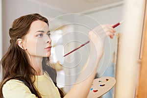 Student girl with easel painting at art school