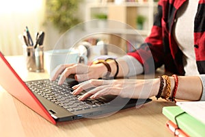 Student girl hands typing on red laptop at home