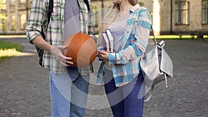 Student girl holding books and chatting with athletic man near college, flirt