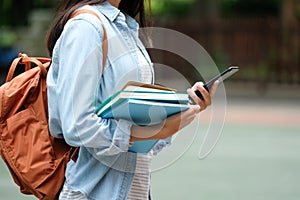 Student girl holding books and using smartphone, online education, technology communication