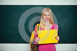 Student girl holding empty faper for product. Learn with fun. Funny female teacher sitting at her workplace and teaching