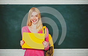 Student girl holding empty faper for product. Learn with fun. Funny female teacher sitting at her workplace and teaching