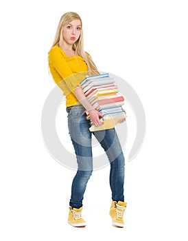 Student girl holding heavy stack of books