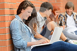 Student girl with laptop and friends outside