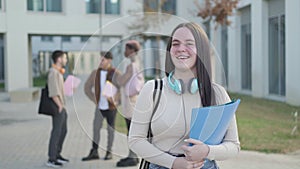 student girl looking at camera while her friends are behind talking, in university campus