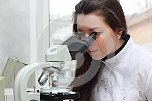 Student girl looking in a microscope, science laboratory concept