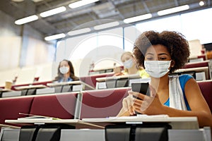 Student girl in mask with smartphone at lecture