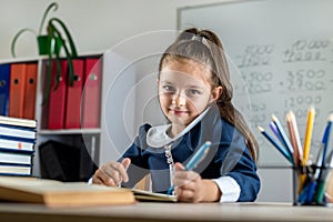 student girl politely listens to the teacher during the lesson in the classroom.